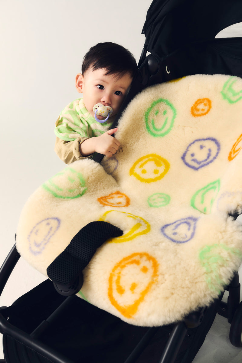 baby hiding behind buggy with sheepskin snuggler
