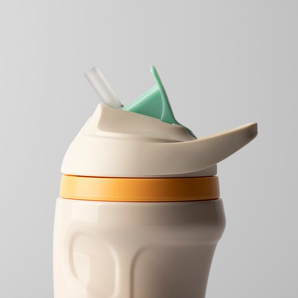 Close up of cream insulated sporty straw cup against a light grey background