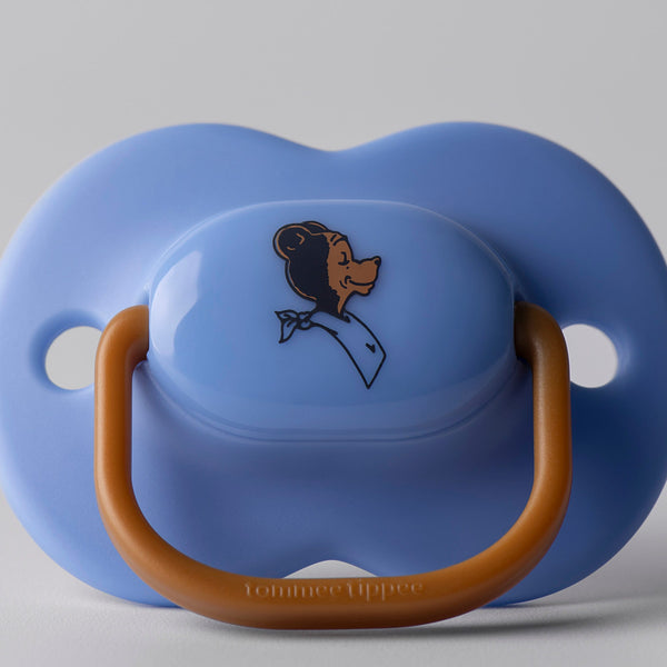 Image en gros plan d'une sucette de tout temps sur un fond gris montrant la décoration de l'ours Tommee Tippee