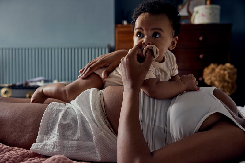 mother laying down with baby on her stomach