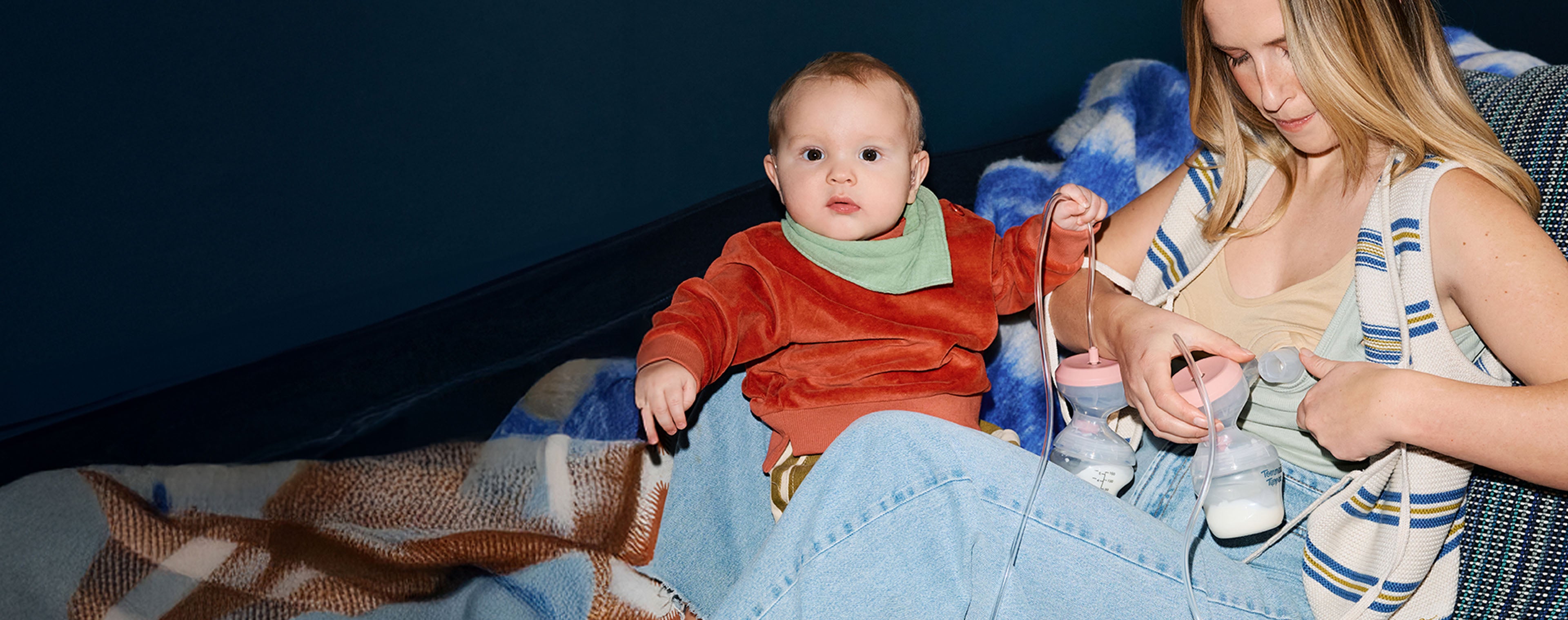Mum and baby sat on sofa whilst mum uses Tommee Tippee Double Electric Breast Pump