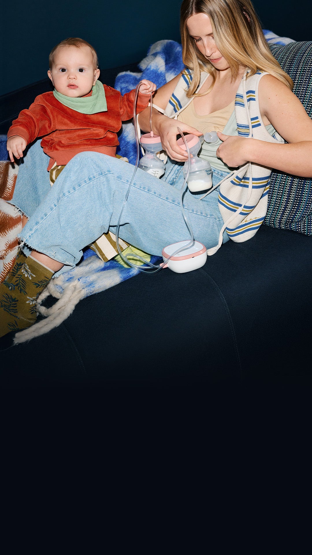 Mum and baby sat on sofa whilst mum uses Tommee Tippee Double Electric Breast Pump