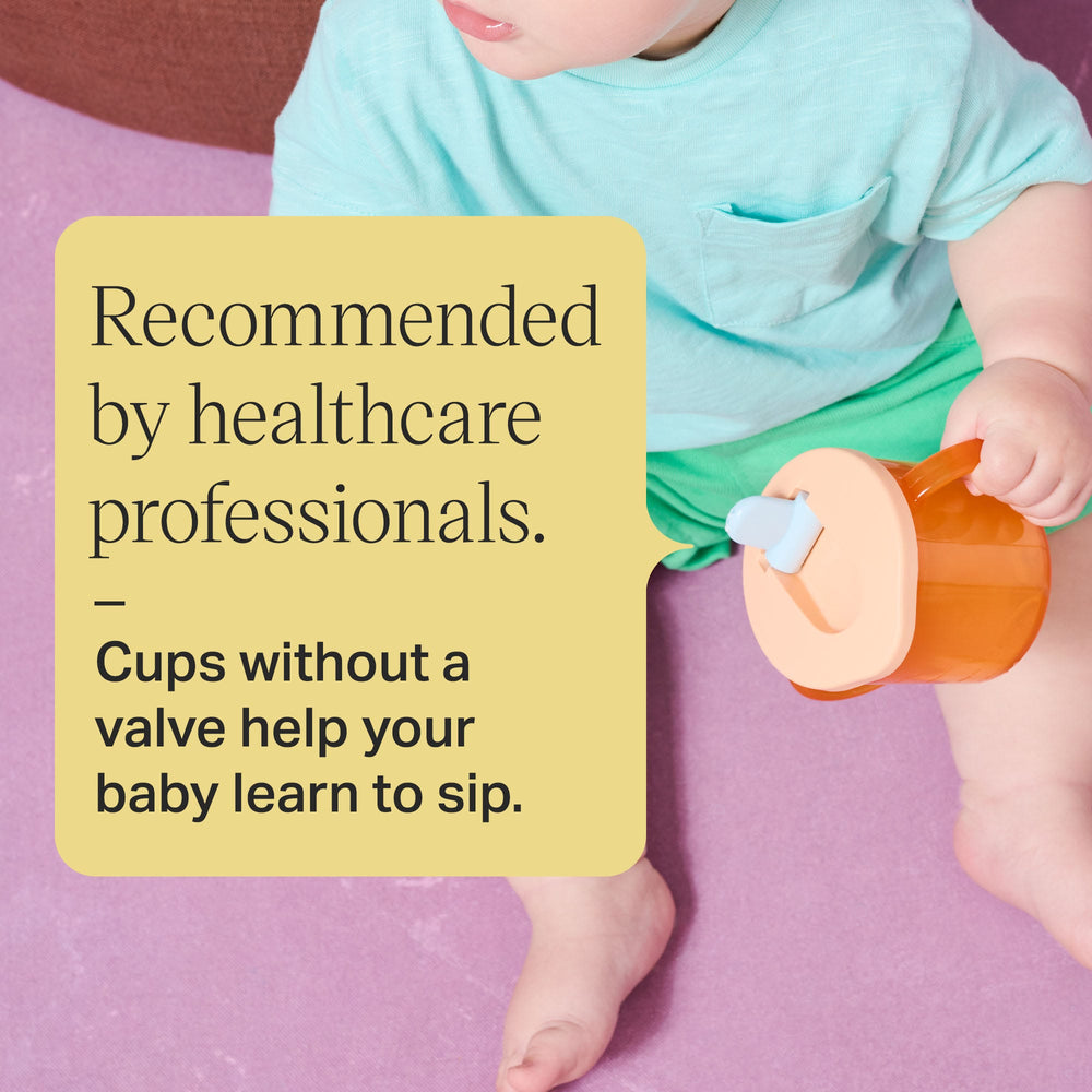 Toddler sitting on the floors holding an orange first cup with text overlay about how free-flow cups are recommended by healthcare professionals