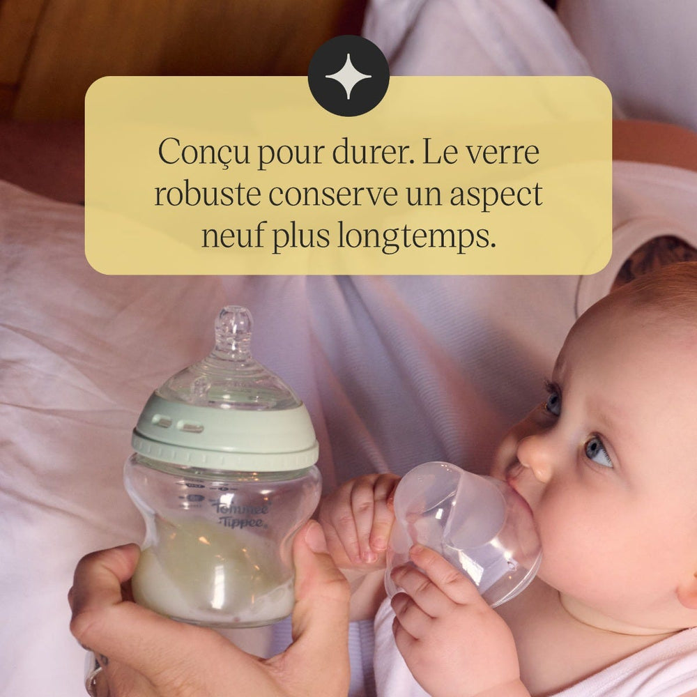 Un parent assis sur son lit avec son bébé tenant un biberon en verre Tommee Tippee Natural Start avec le texte suivant : « Conçu pour durer. Le verre résistant reste comme neuf plus longtemps. »