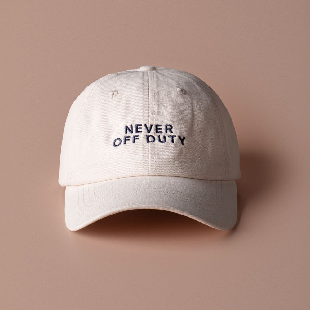 The front of the Never off duty white cap on brown background
