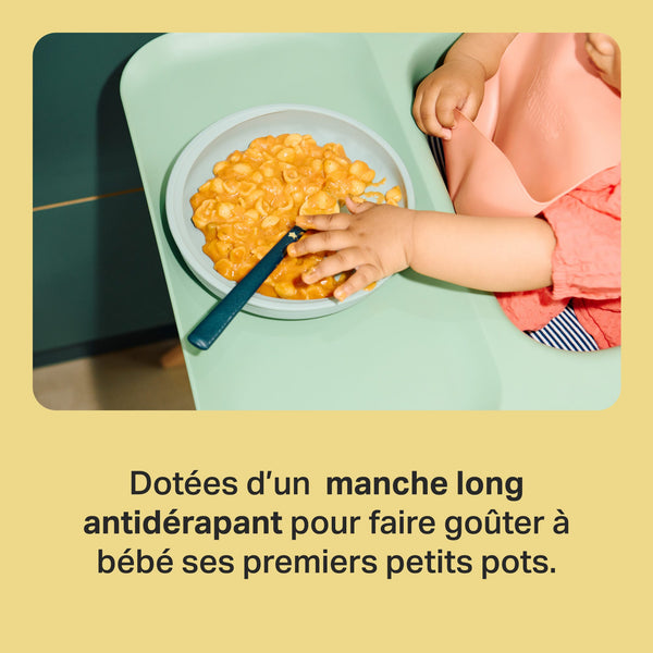 Bébé dans une chaise haute saisissant la cuillère de sevrage avec un texte sur les poignées antidérapantes.