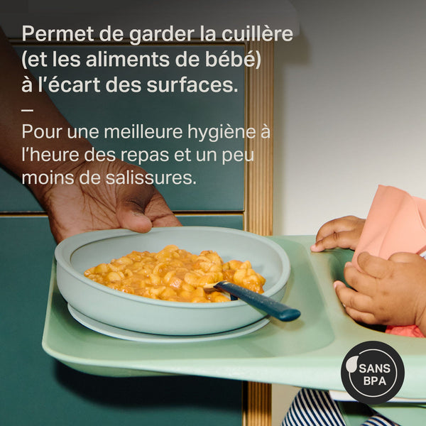 Parent plaçant une assiette de sevrage en silicone avec cuillère sur la chaise haute de bébé avec un texte de présentation.