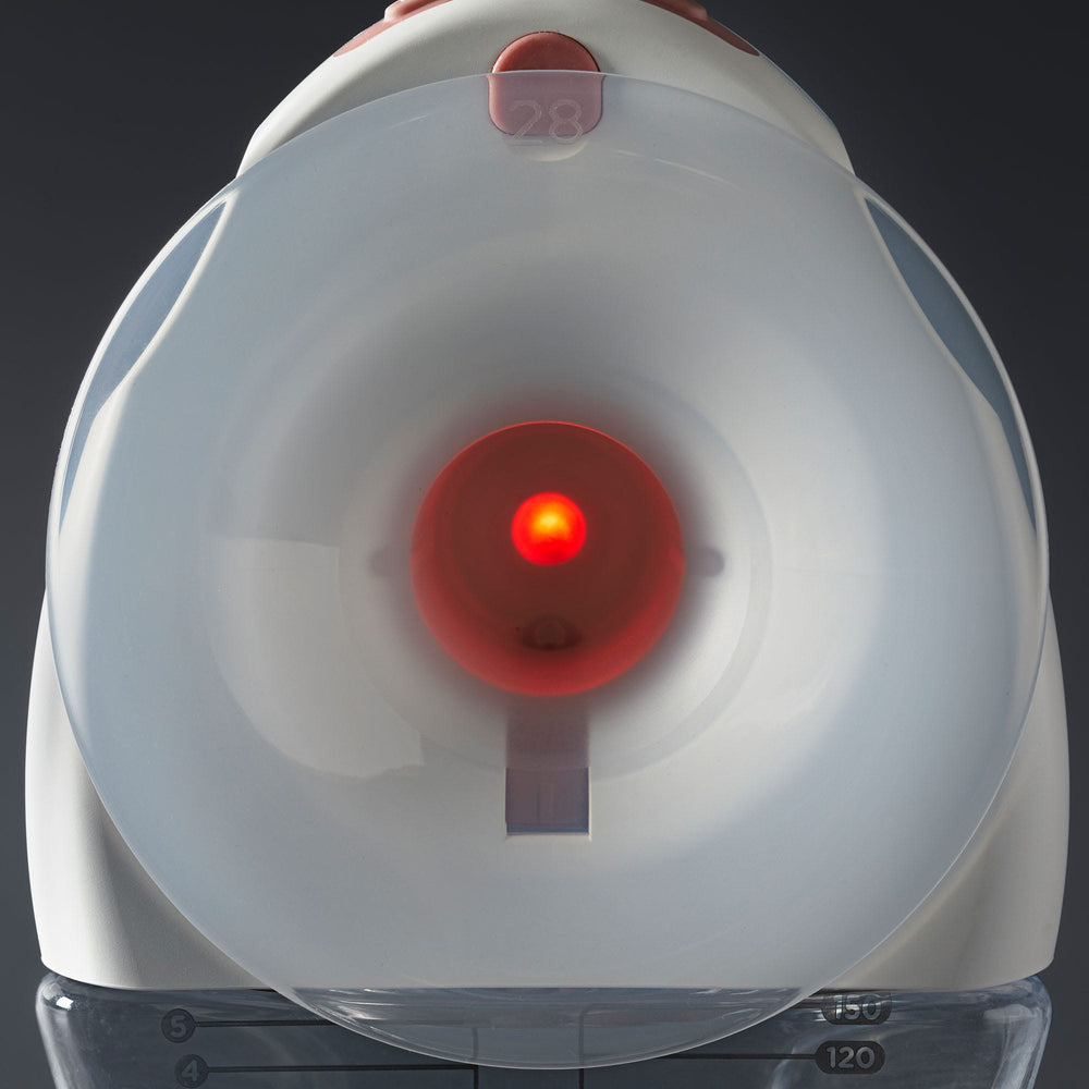 Wearable breast pump with nipple alignment light connected to a milk collector bottle.