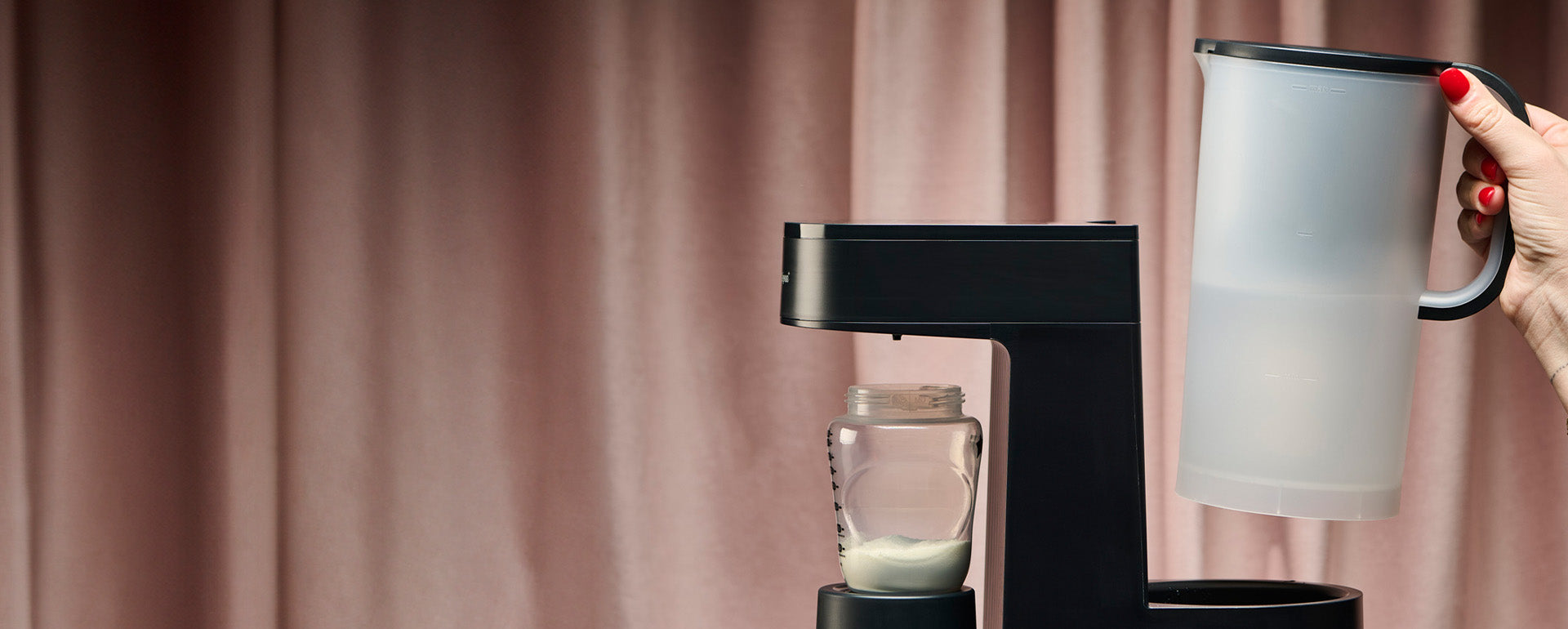 Hand holding Perfect Prep® jug infront of pink curtain