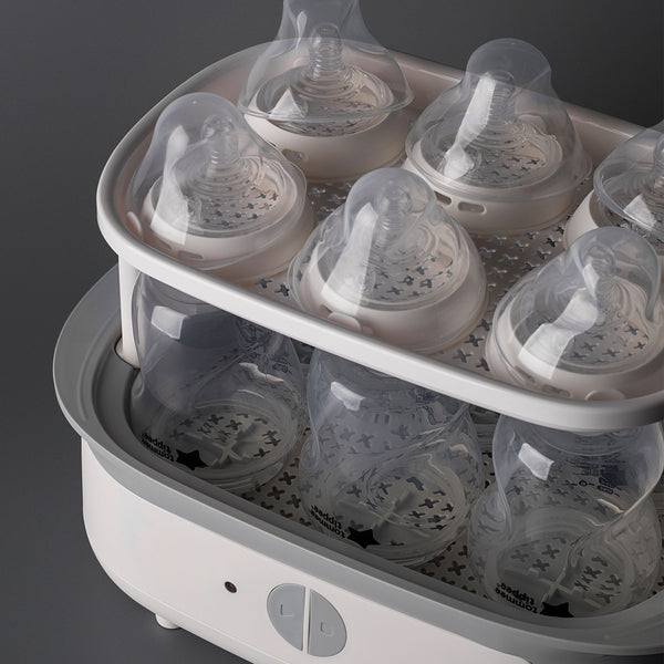 Steam steriliser open and filled with bottles against a grey background