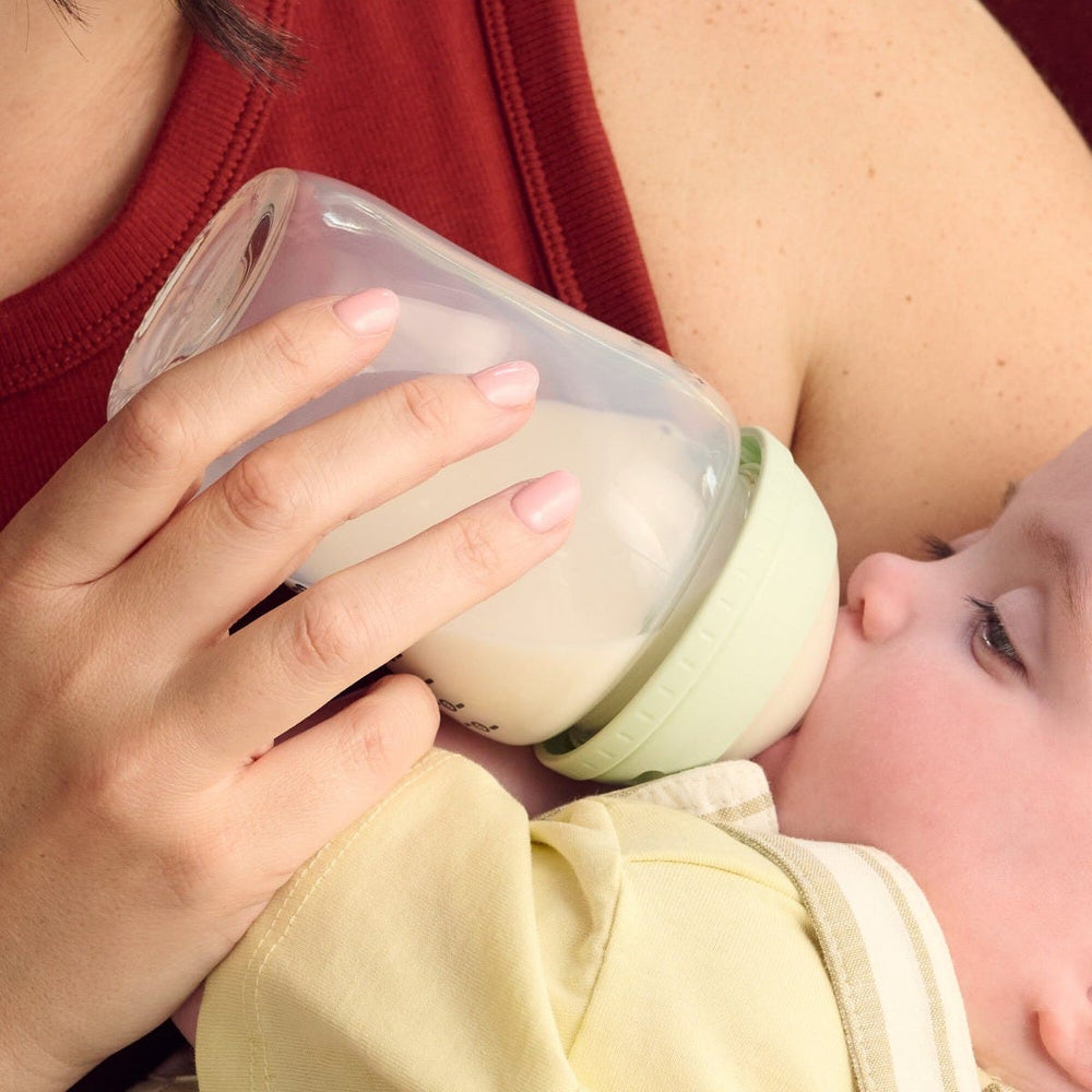 Woman feeding her baby using a Tommee Tippee Natural Start glass baby bottle