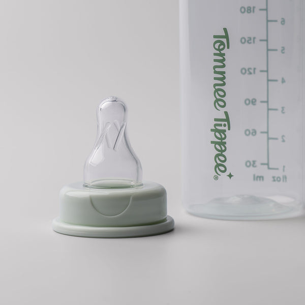 Bottle teat sitting on a grey surface alongside a Classic Start narrow neck bottle