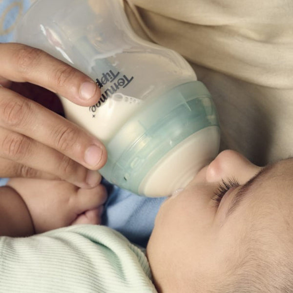 Close up image of a parent feeding a baby using an Advanced Anti-colic bottle
