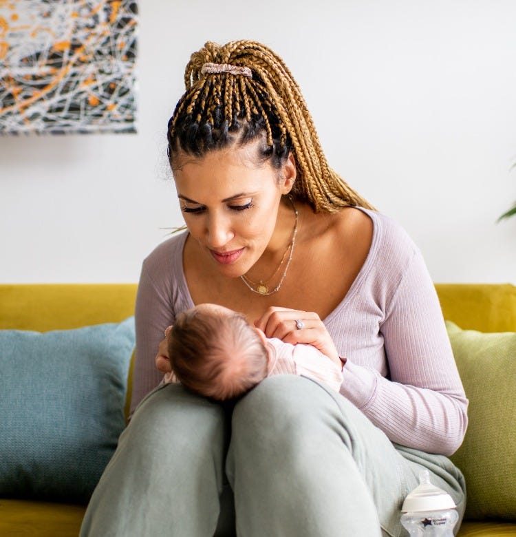 Due Date Stories from Australian Parents mum sitting on the sofa holding her newborn baby