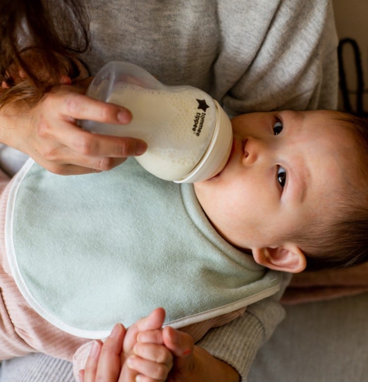 Why Your Baby Is Crying During Feeding mum bottle feeding her baby using a tommee tippee bottle
