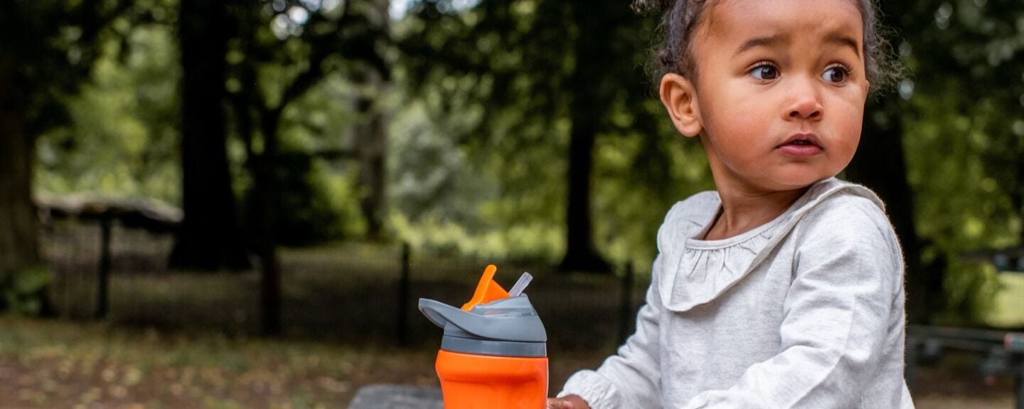 How to Help Fussy Eaters toddler playing in the park with an orange cup