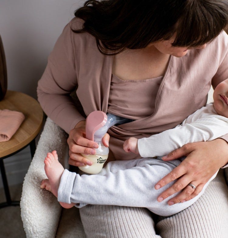 All You Need to Know About Tongue Tie mum sitting on a sofa holding her baby and using a manual breast pump