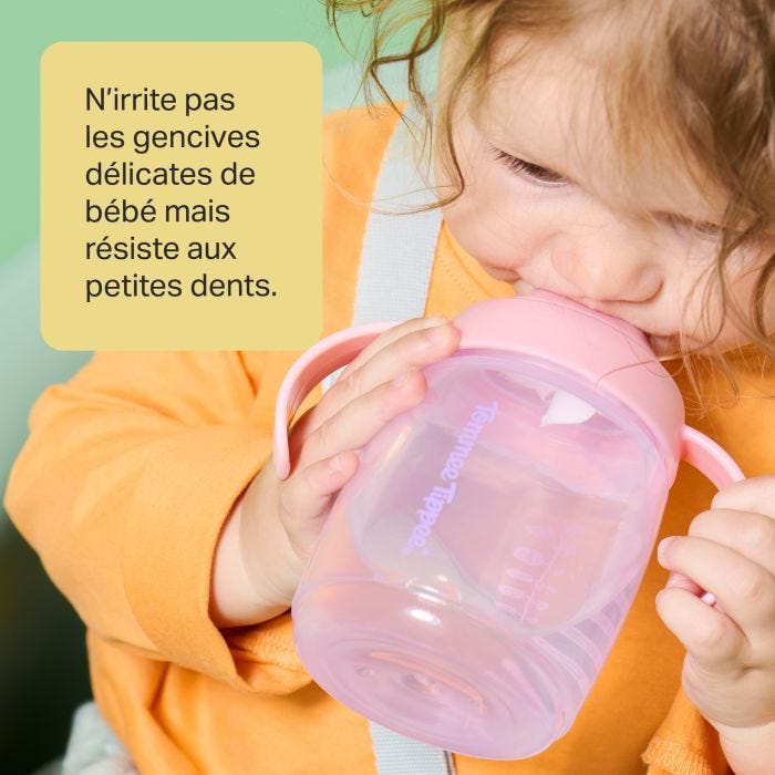 Enfant en bas âge buvant dans un gobelet à bec d&apos;entraîneur rose avec texte en surimpression de messages sur le produit