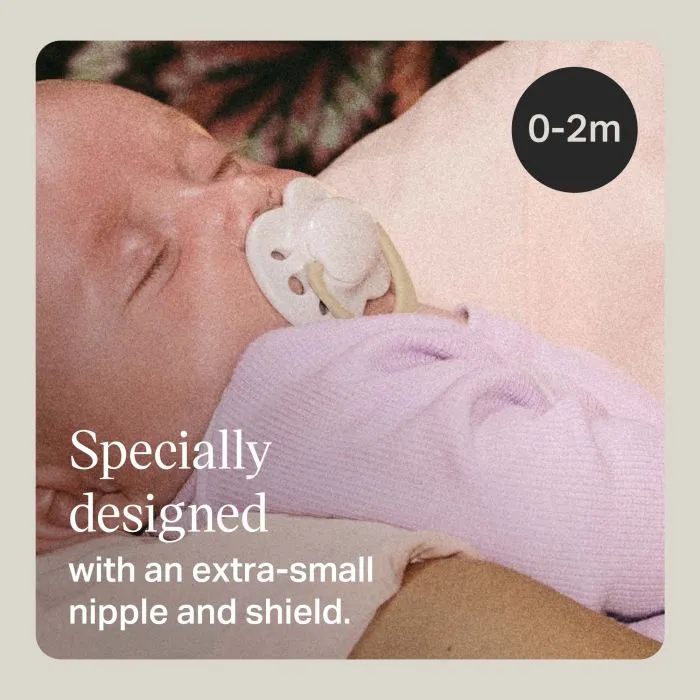 Newborn baby with paci in mom's arms with text about the tiny shield and nipple.