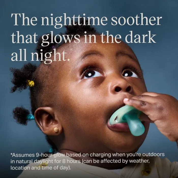 Baby looking up and holding a night glow soother.