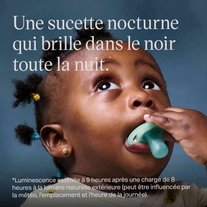 Bébé levant les yeux et tenant une sucette lumineuse.