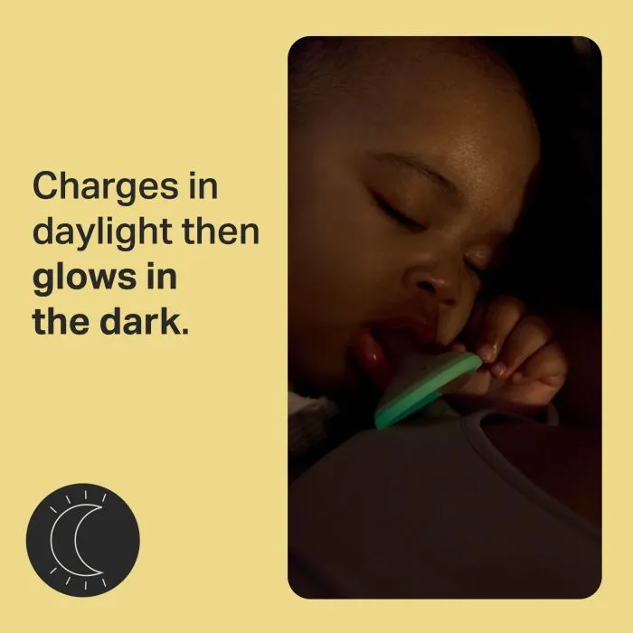 Baby with an illuminated pacifier with text about glowing in the dark.