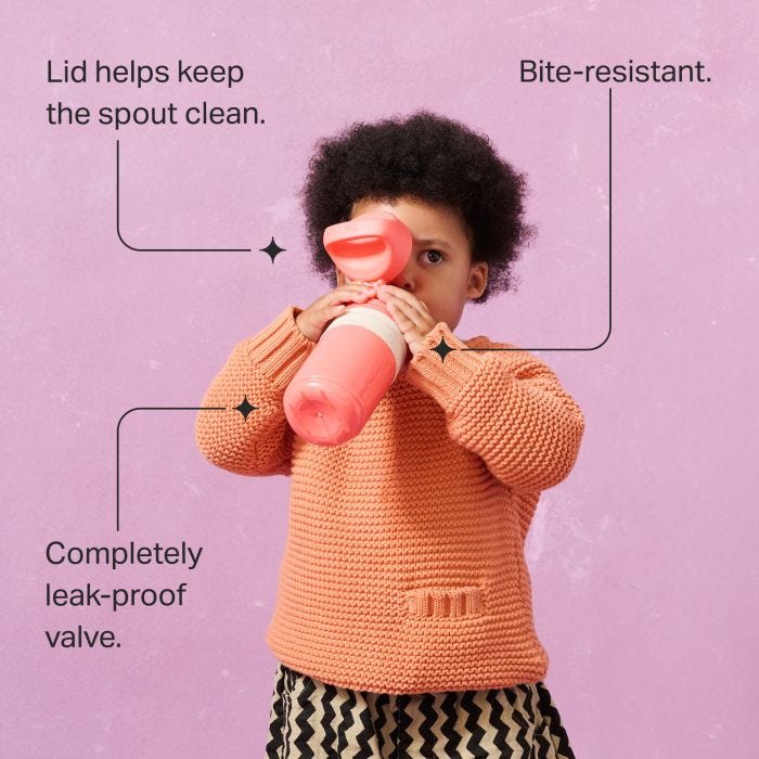 Toddler drinking from an on-the-go straw cup against a pink background with pointers to the product key features