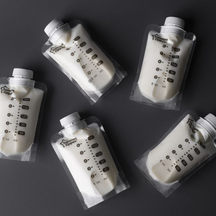 Five sealed breast milk pouches containing milk ona  dark grey background.