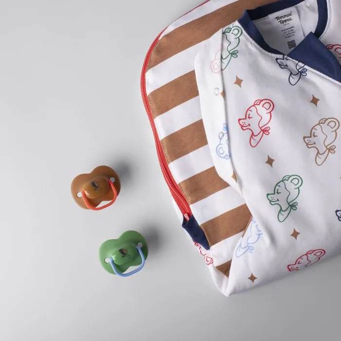Sac à langer plié et deux sucettes Anytime sur fond gris clair.