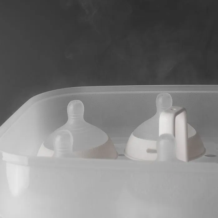 Open SteriDryer with steam coming out of it and showing bottle lids inside against a grey background