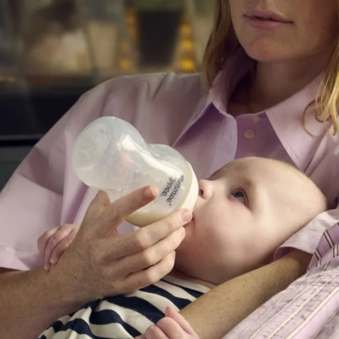 Close up image of a woman feeding a baby using a Natural Start bottle