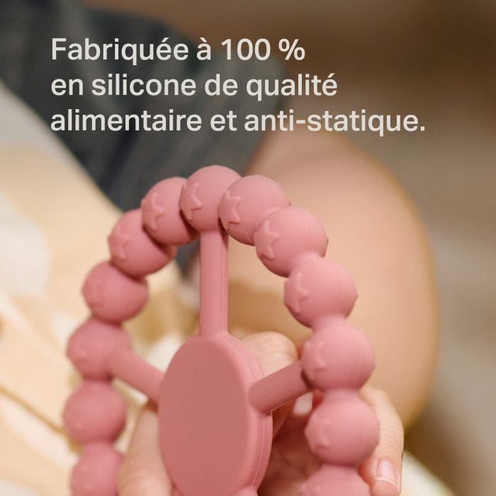 Bébé mordille l&apos;anneau à bascule avec l&apos;avis d&apos;un parent.
