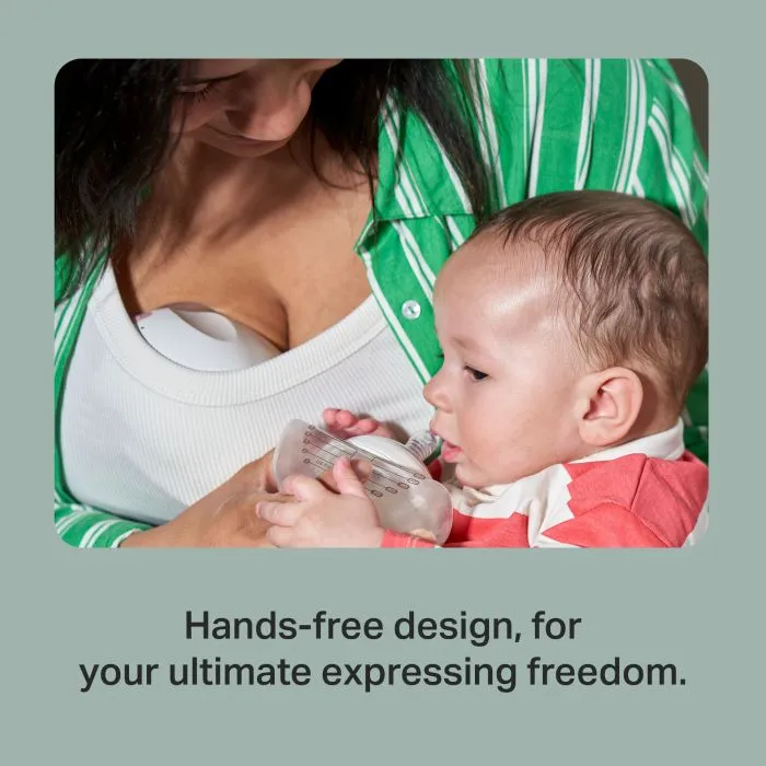 Parent expressing with our in-bra Wearable Breast Pump while feeding a baby.