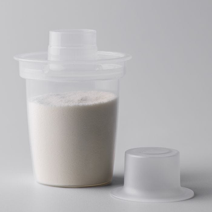 Dispenser containing formula on a light grey background.