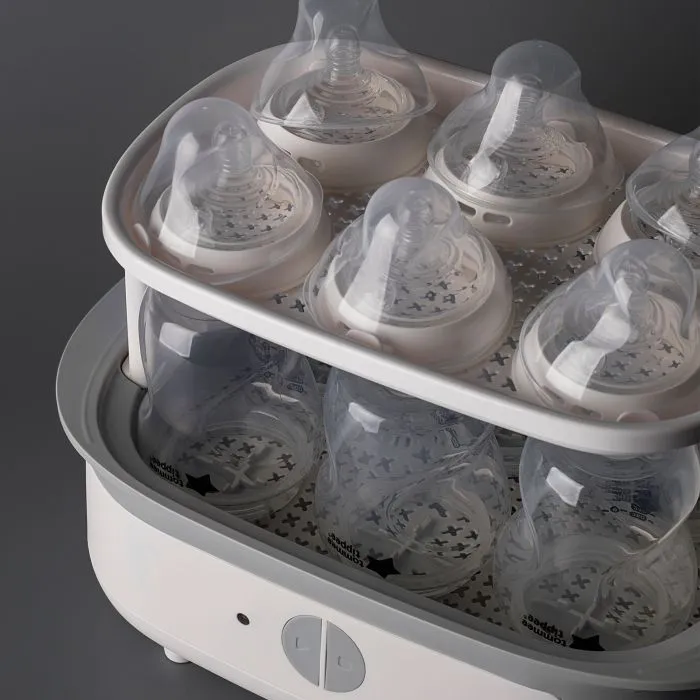 Steam steriliser open and filled with bottles against a grey background