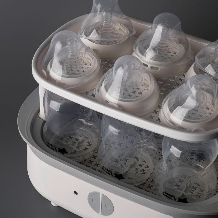 Steam steriliser open and filled with bottles against a grey background
