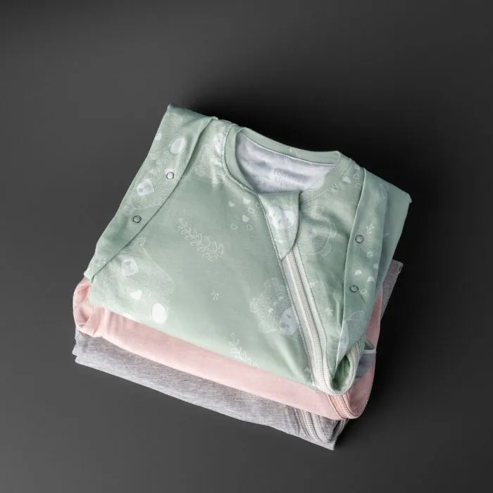 Three folded sleeping bags on a grey background