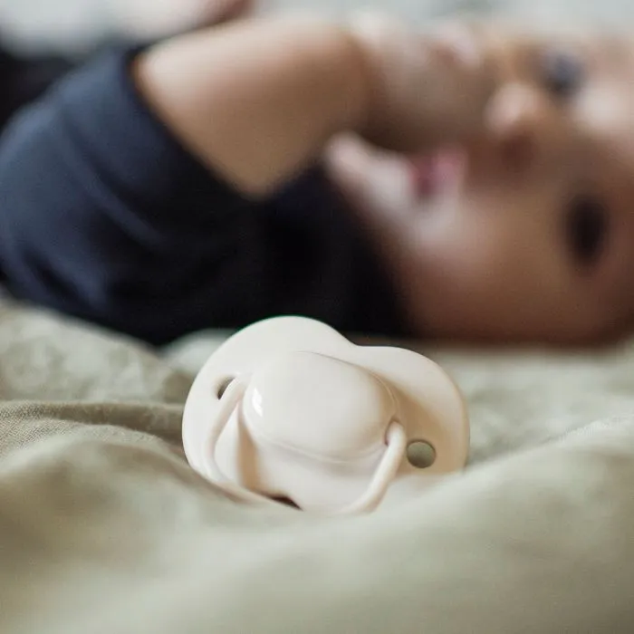 Close up of soother on bed next to baby