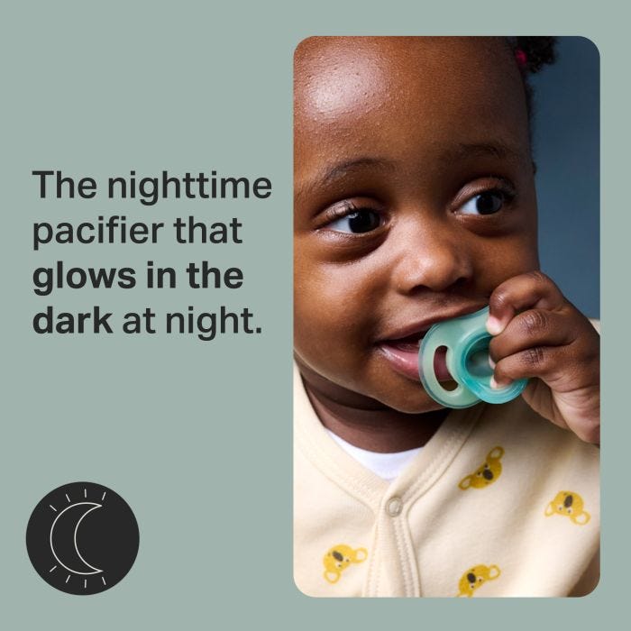 Baby holding a pacifier in their mouth with glow in the dark feature call-out.