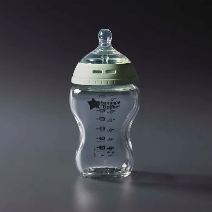 Glass baby bottle against a grey background
