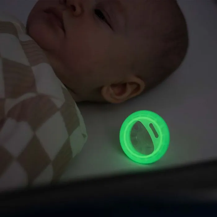Baby sleeping with glowing in the dark pacifier next to them