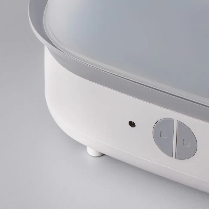 Close up of the buttons on the front of a steam steriliser against a grey background