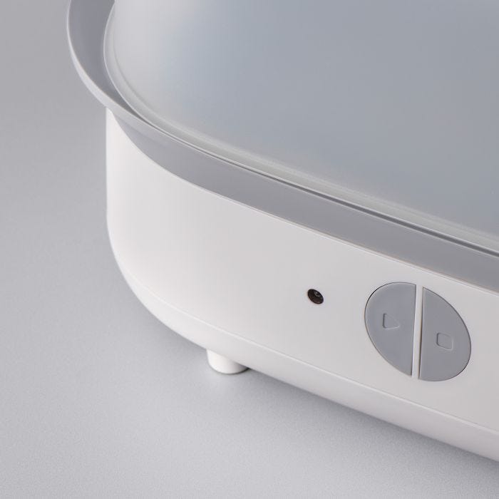 Close up of the buttons on the front of a steam steriliser against a grey background