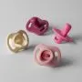 Four Ultra-light StayPut pacifiers on a grey background.