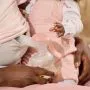 Parent manually expressing while holding baby.