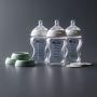 Three 9oz glass baby bottles next to three travel jar lids and three cup rings.