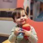 Toddler holding a blue and red sippee cup while smiling