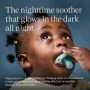 Baby looking up and holding a night glow soother.