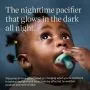 Baby looking up and holding a night glow pacifier.