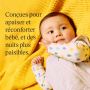 Un bébé douillet allongé sur une couverture jaune texturée, vêtu d&apos;une grenouillère à pois et d&apos;une gigoteuse gris clair.